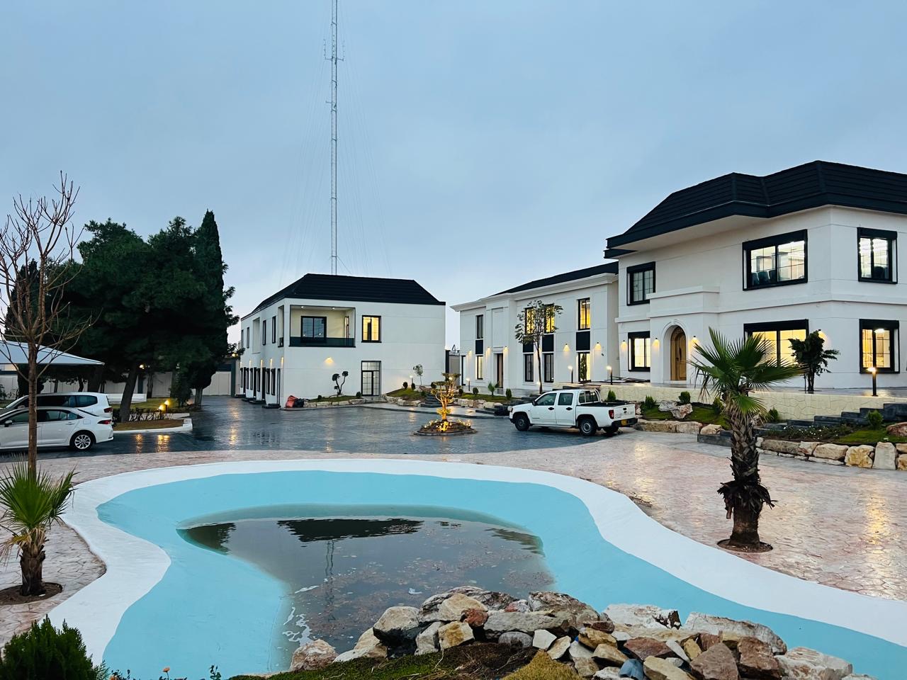The finished compound at dusk: the courtyard pool in front of white two-storey buildings