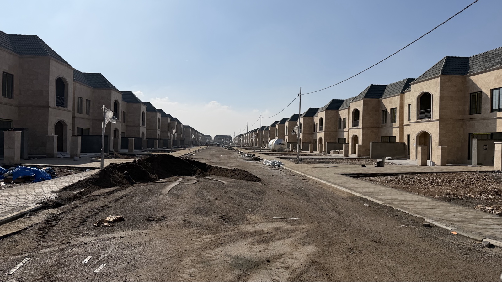 Spanish Village 2, Block A: a street of stone-clad villas with tiled roofs under construction