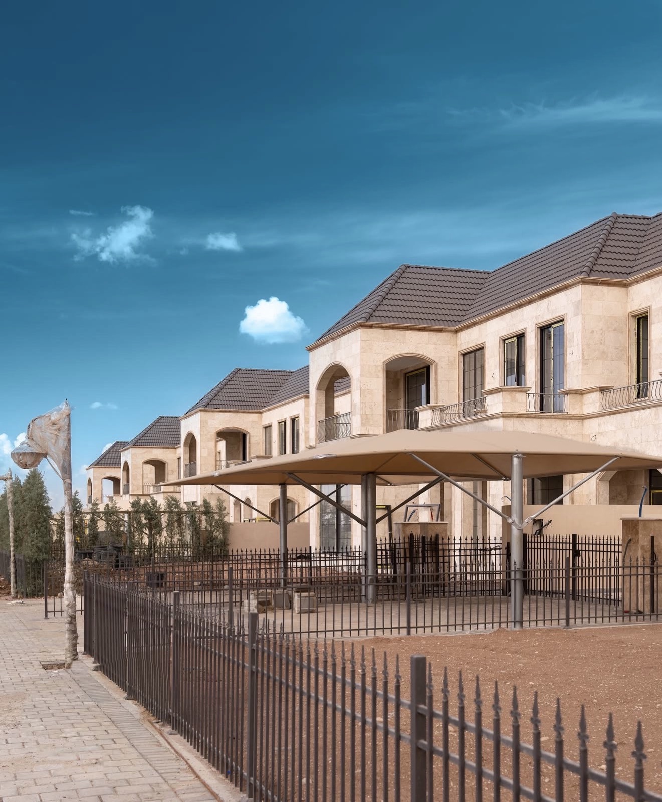 Spanish Village 2: finished villas with arched balconies behind a shaded seating area and iron fence