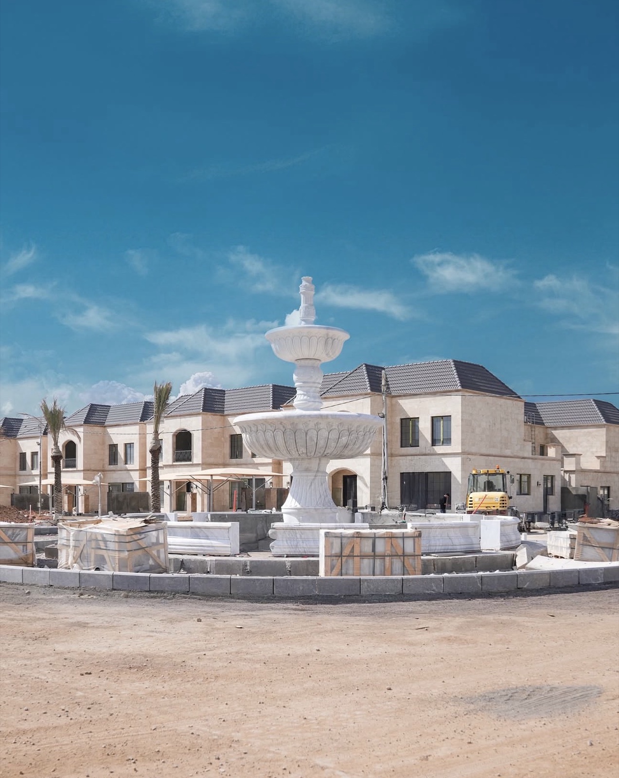 Spanish Village 2: a white stone fountain being set on a roundabout in front of the villas